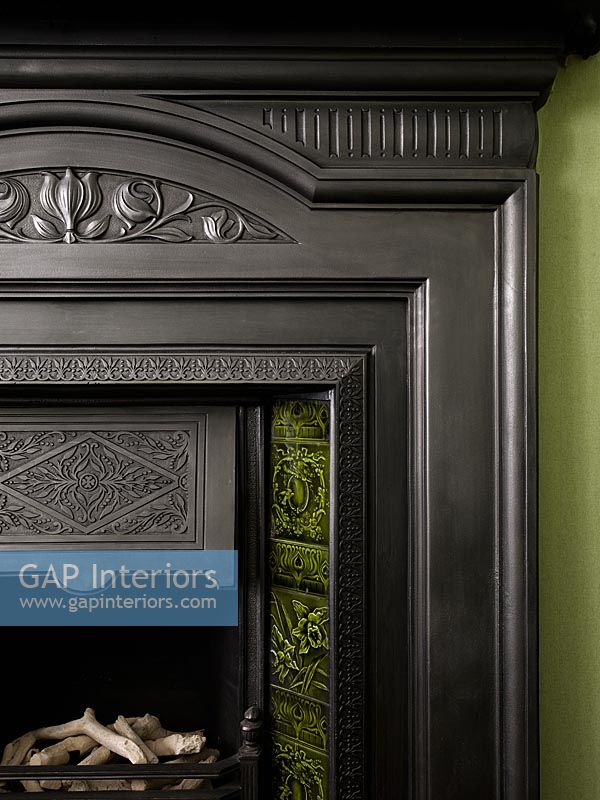 Detail of black fireplace with green inlaid tiles 