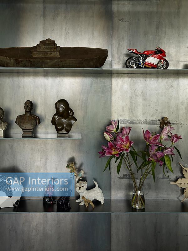 Ornaments and flowers on shelves with concrete wall behind 