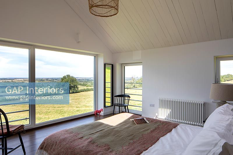Modern bedroom with large windows and panoramic views of the countryside 