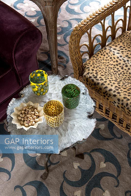 Wicker chair with leopard print cushion and decorative glassware on table 