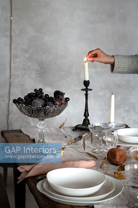 Woman lighting candle on country dining table 