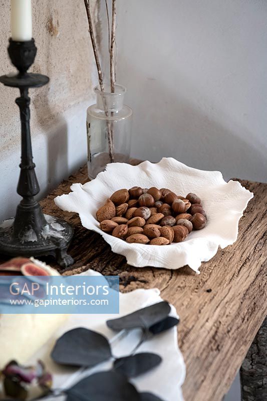 Decorative ceramic bowl of harvested nuts in their shells on rustic table