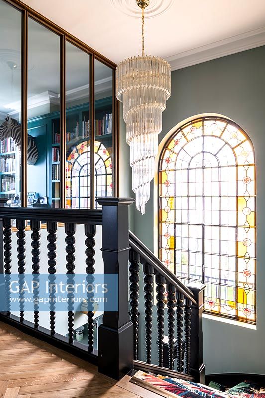 Large chandelier over staircase with stained glass window