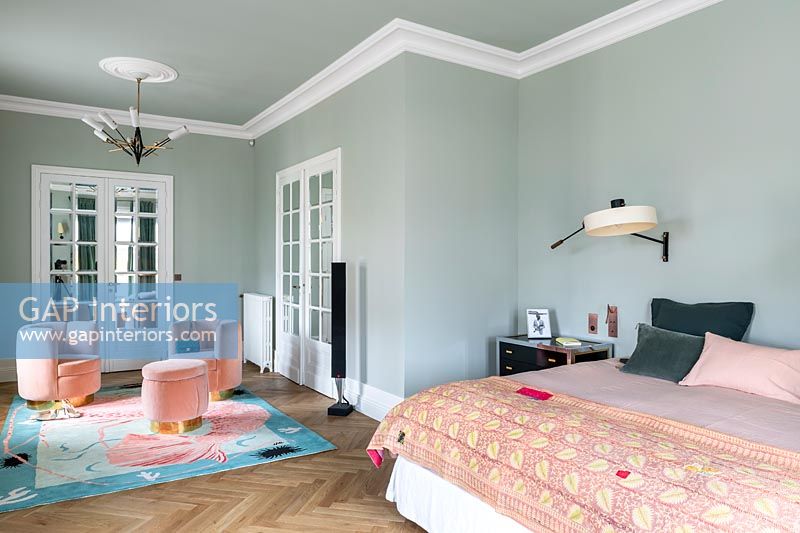 Pink seating on colourful rug in green painted bedroom 