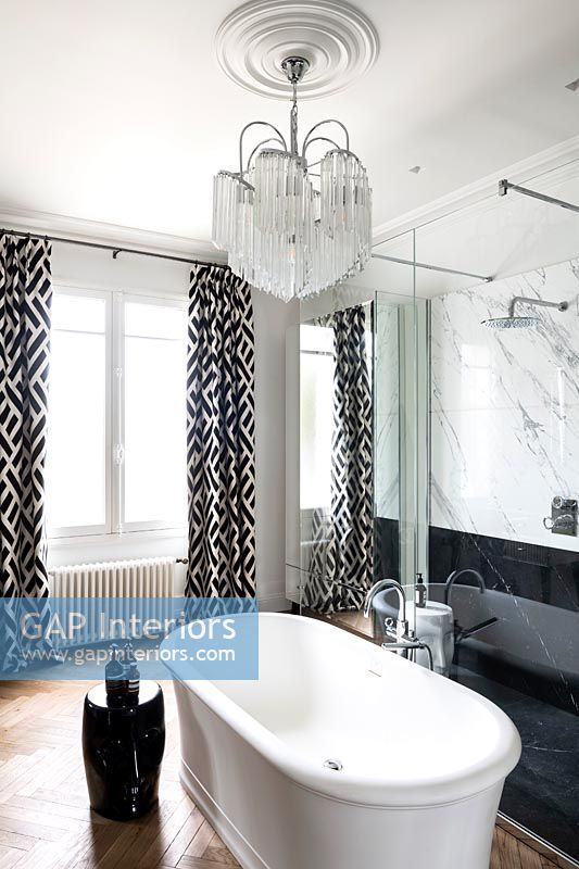 Freestanding bath and chandelier in modern black and white bathroom 