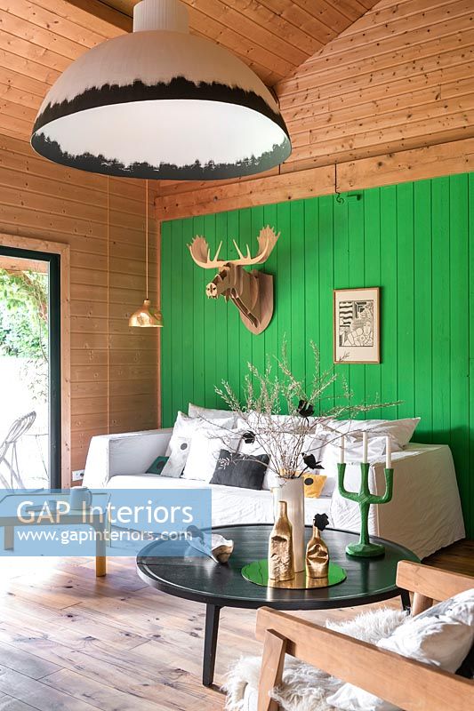 Carved wooden trophy animal head on bright green wall in modern living room