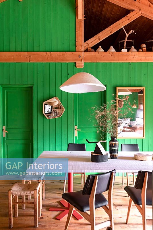 Modern country dining room with green painted wooden wall 