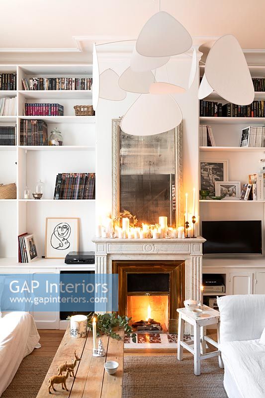Lit fireplace and candles in white living room at Christmas 