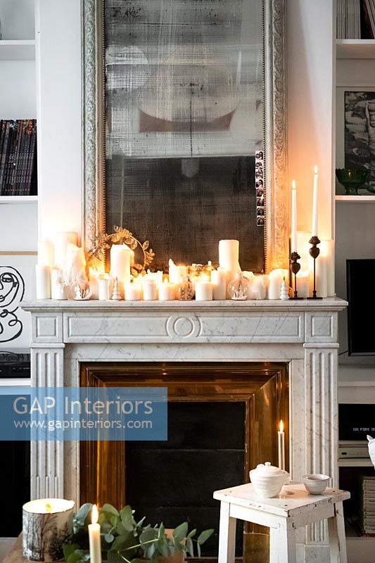 Display of lit candles on white mantelpiece 