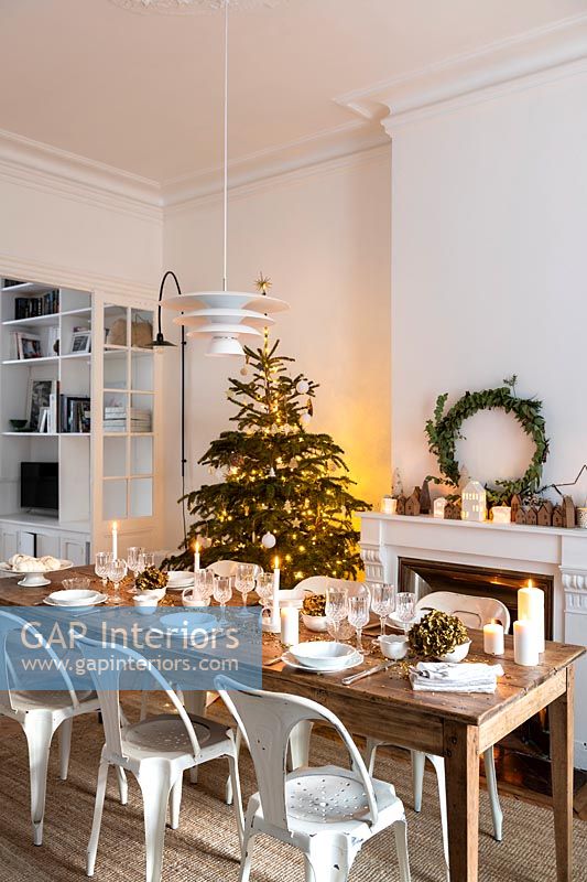 Wooden dining table laid for Christmas dinner in white dining room 