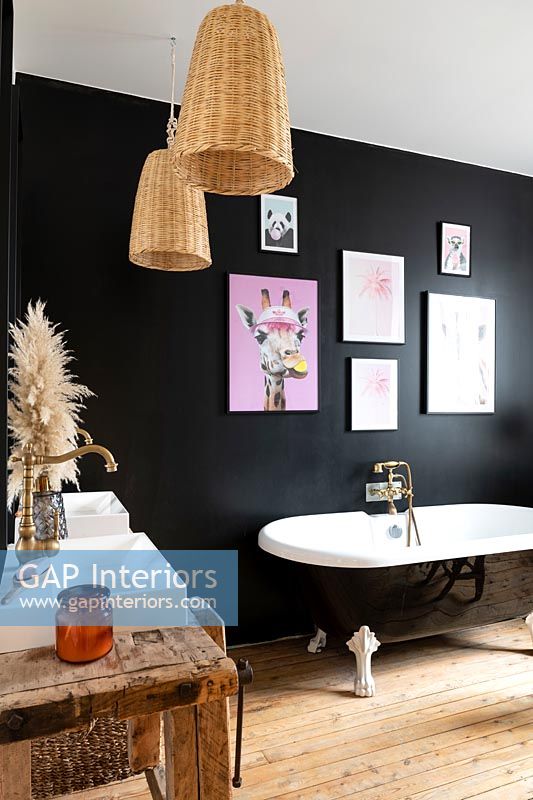 Roll top bath in modern bathroom with black painted feature wall 