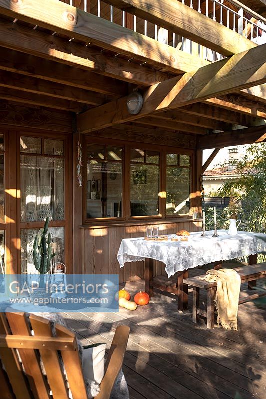 Outdoor dining area on decking next to wooden country cabin 