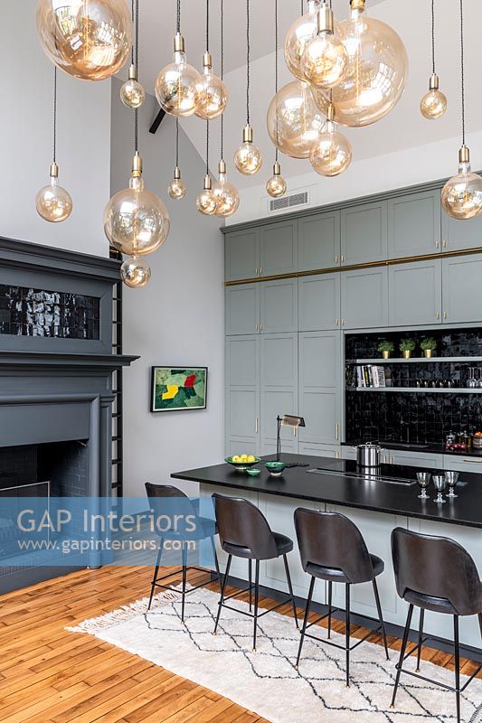 Modern kitchen with grey painted fireplace and display of pendant lights
