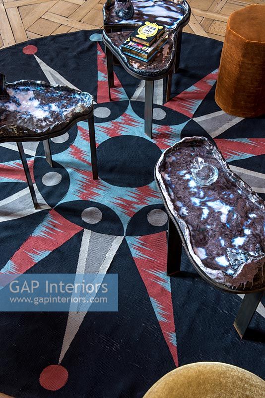 Circular patterned rug with unusual side tables 