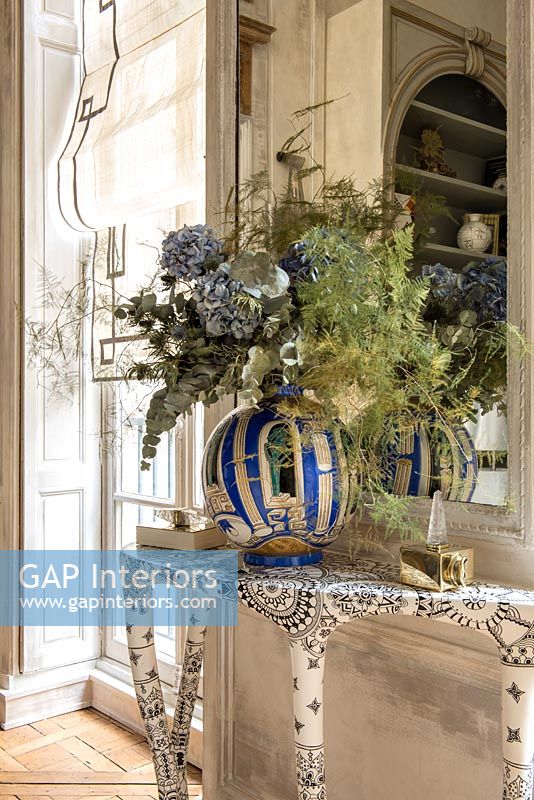 Huge blue and white vase of flowers on patterned console table 