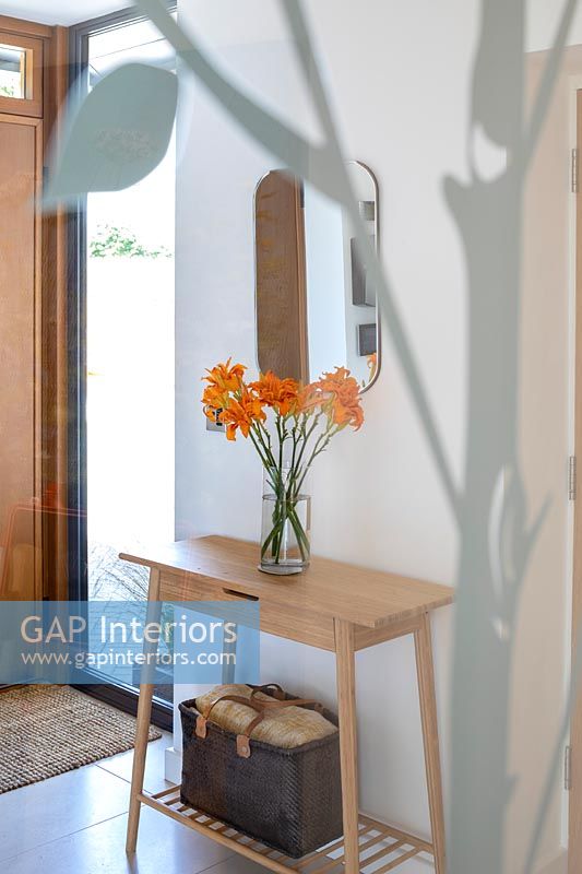 Flowers on small wooden modern console table in hallway 