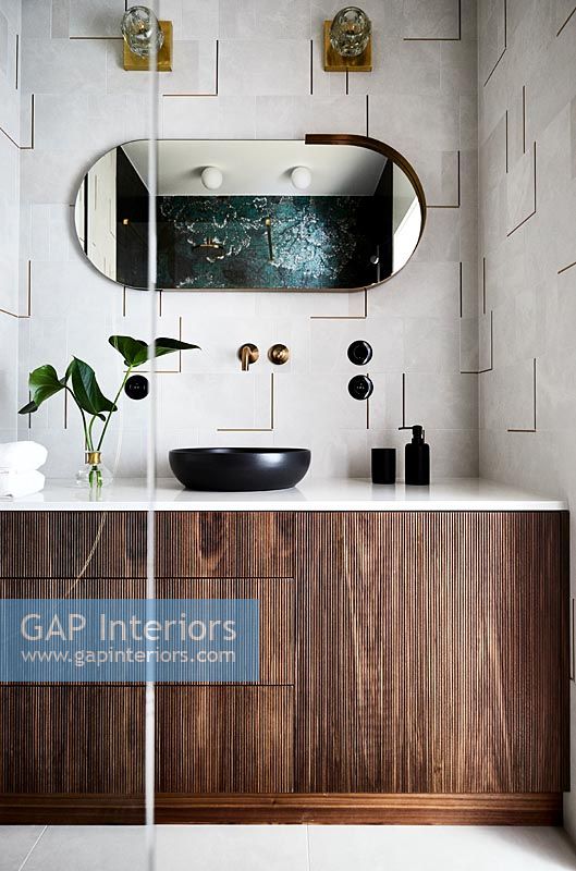 Modern bathroom with textured tiling on wall and wooden cabinet
