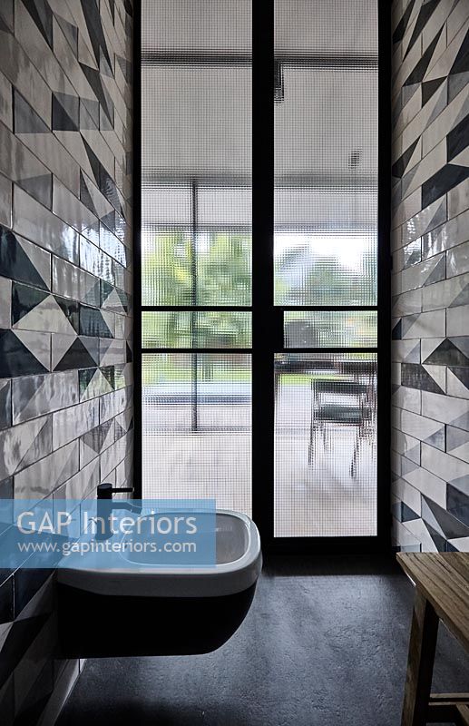 Modern bathroom with patterned tiling on wall 