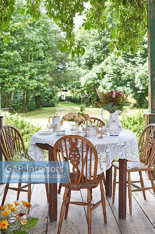 Afternoon tea on wooden terrace overlooking country garden 