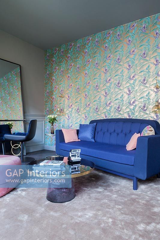 Wall paper on feature wall behind blue sofa in modern living room  