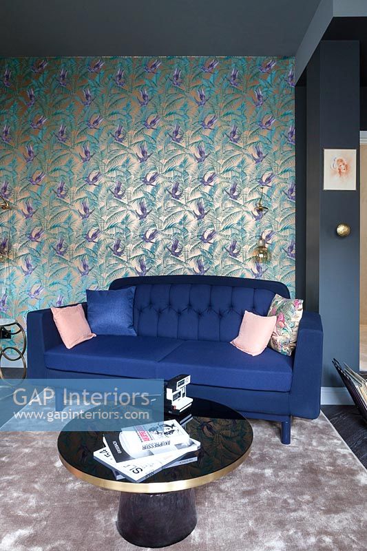 Wall paper on feature wall behind blue sofa in modern living room  