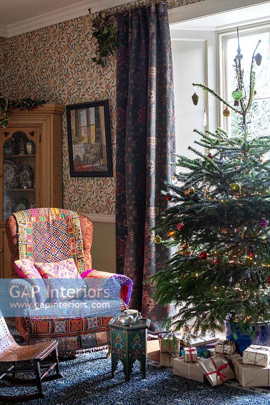 Colourfully patterned armchair next to Christmas tree 