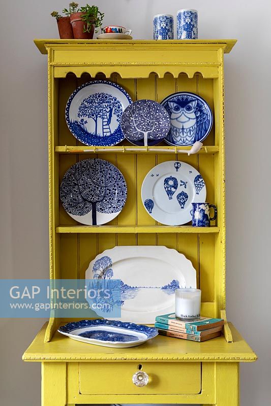Yellow painted small wooden dresser with display of blue and white plates 