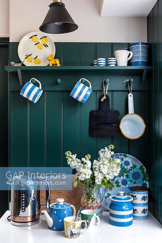 Blue and white crockery in modern kitchen with green painted wall 