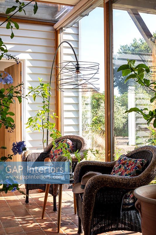 Modern wire floor lamp over rattan chairs in conservatory 