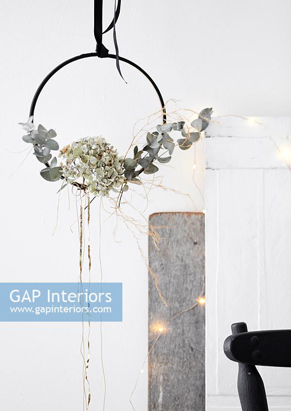 Silver grey foliage displayed on a hanging black hoop with fairy lights 