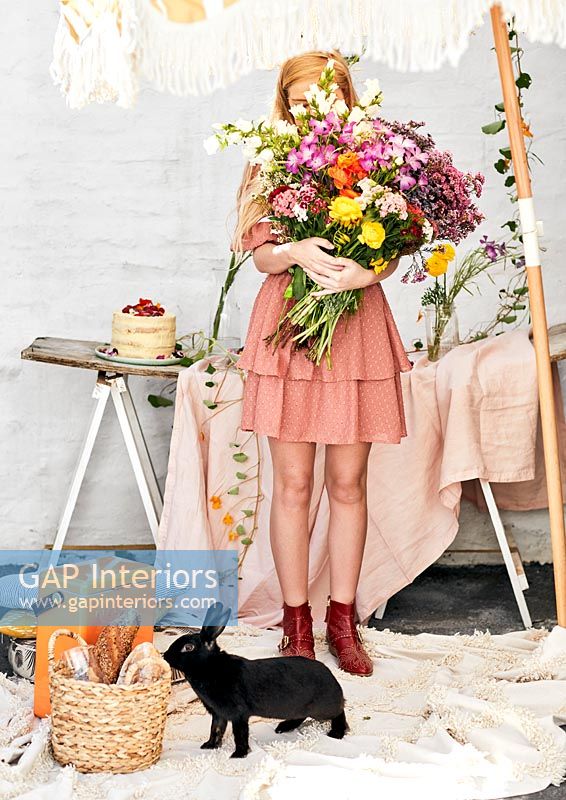 Young woman holding large bunch of cut flowers with pet rabbit