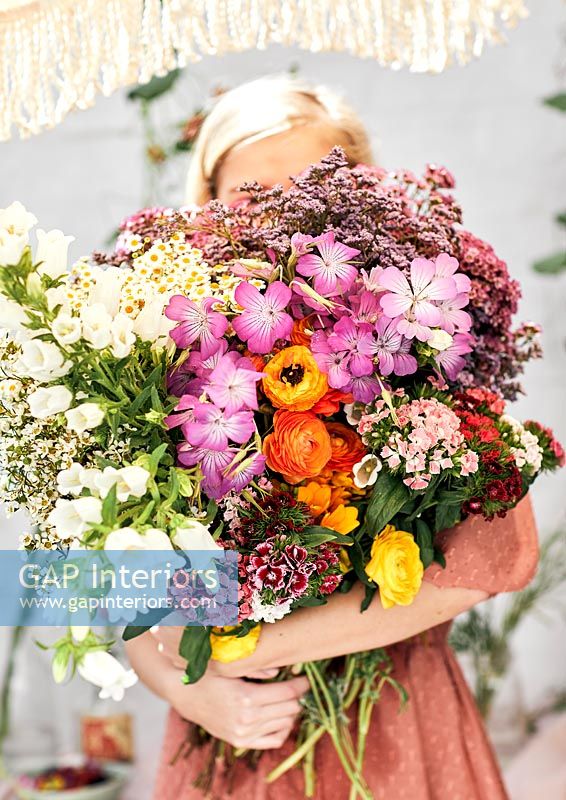 Young woman holding large bunch of cut flowers