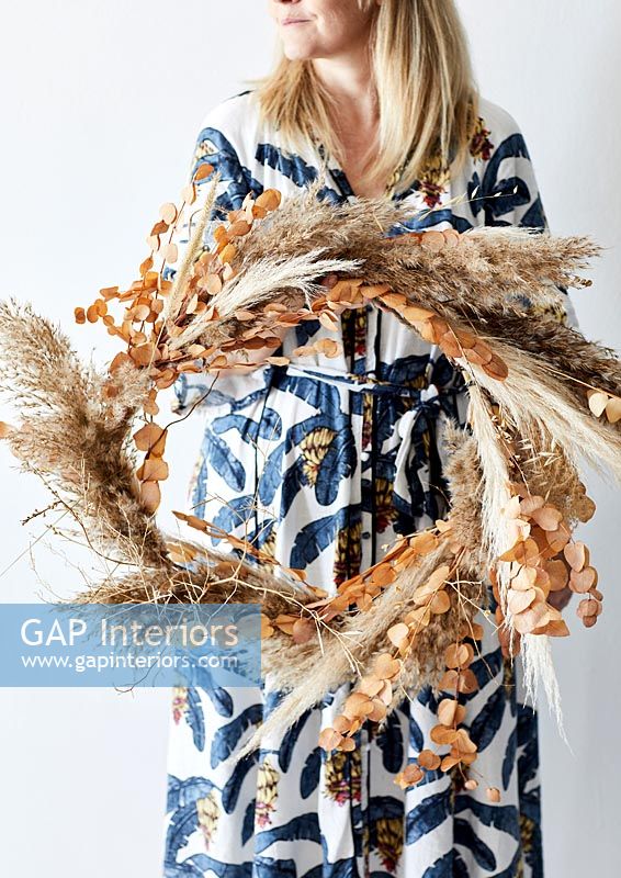 Woman holding dried flower and grass wreath