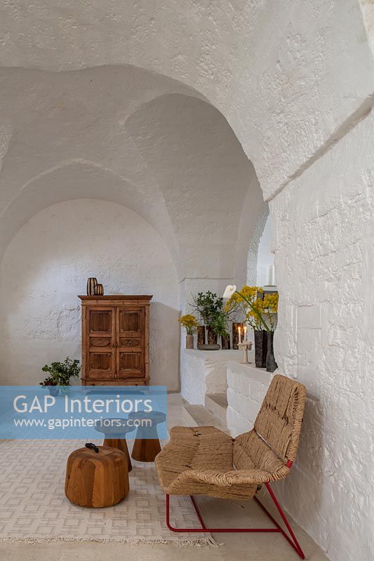 Wooden and wicker furniture against white painted stone walls 