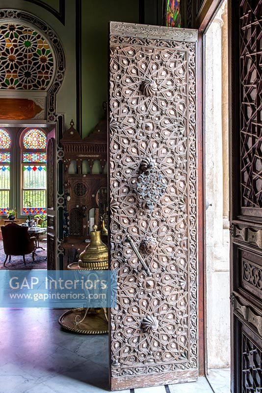 Ornate carved front door open into classic hallway 