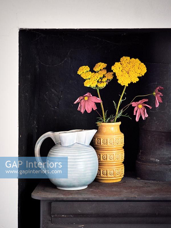 Flowers in vase next to jug with black background 