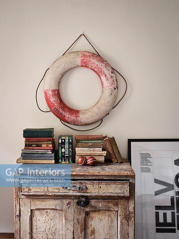 Lifebuoy on wall above distressed cabinet 