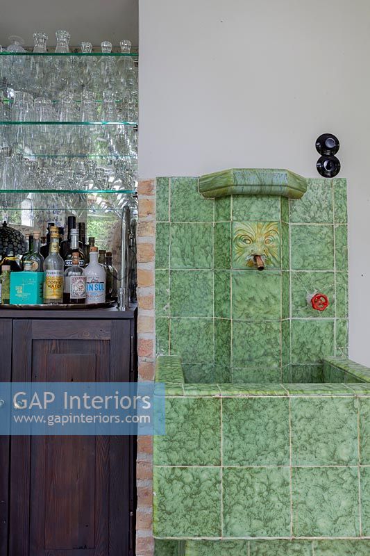 Green tiled water feature - sink next to drinks cabinet 