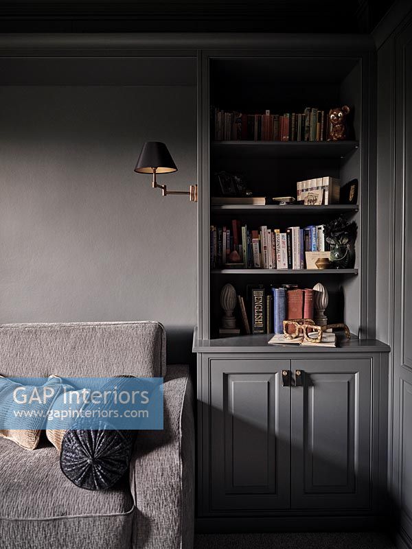 Grey sofa and wooden unit in dark painted living room 