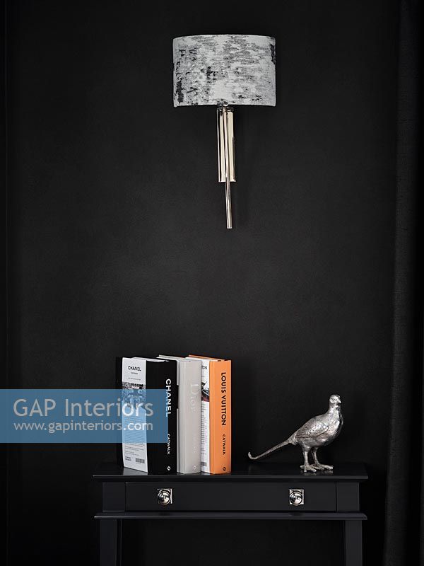 Wall mounted lamp and side table with books and silver bird ornament 