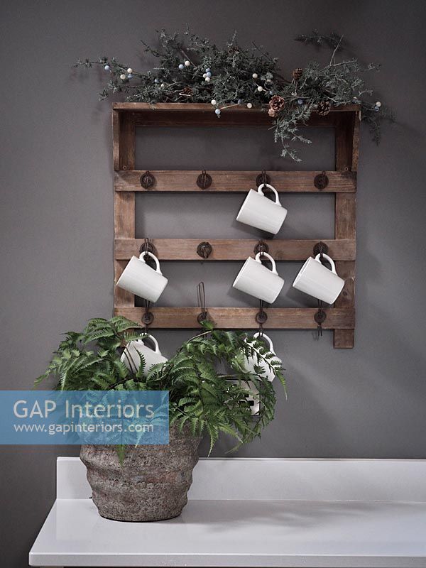Wall mounted wooden shelf with hooks for mugs in modern kitchen 