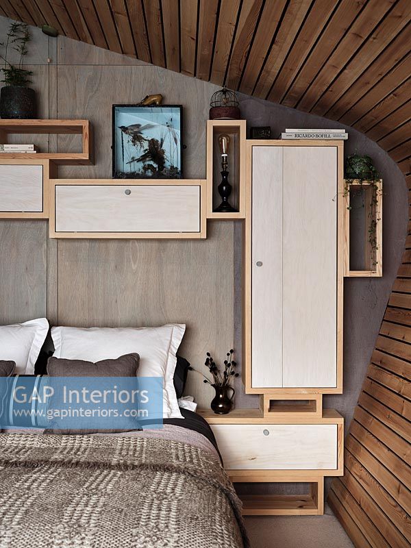 Modern bedroom with network of wall mounted wooden storage cupboards 