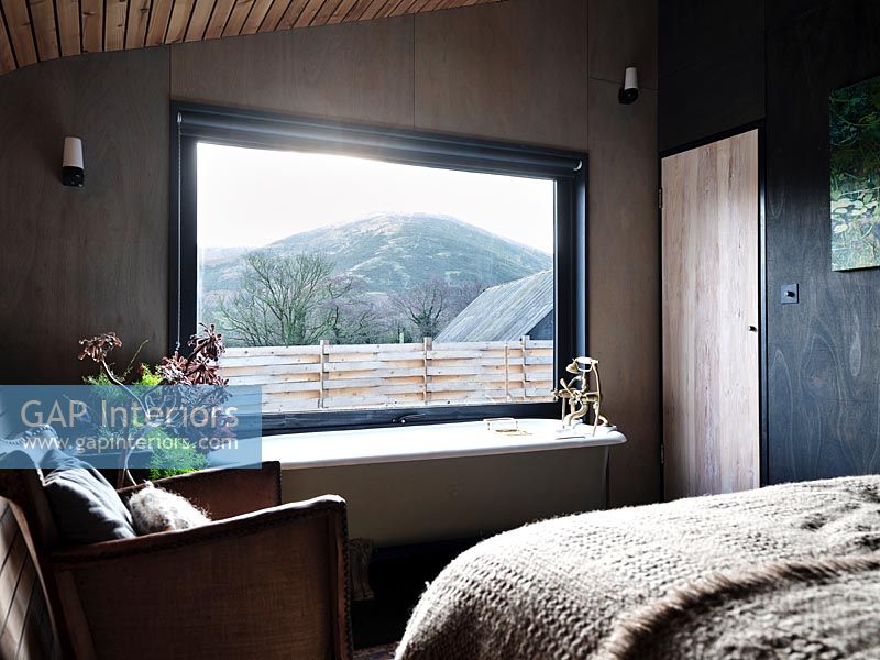 Bath next to window in modern bedroom with scenic views 