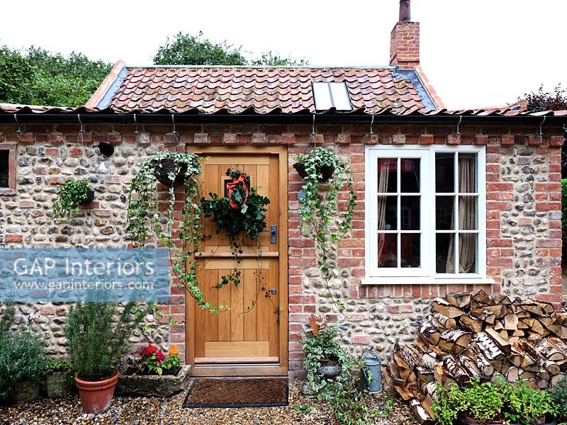 Exterior of small country cottage with decorative wreath on front door 
