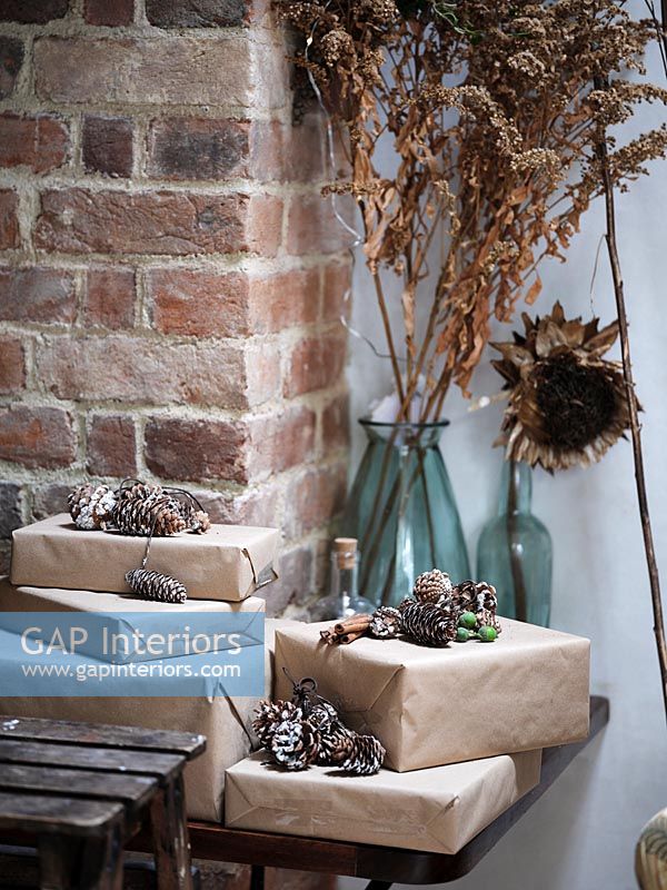 Christmas gifts wrapped in brown paper and decorated with pine cones 