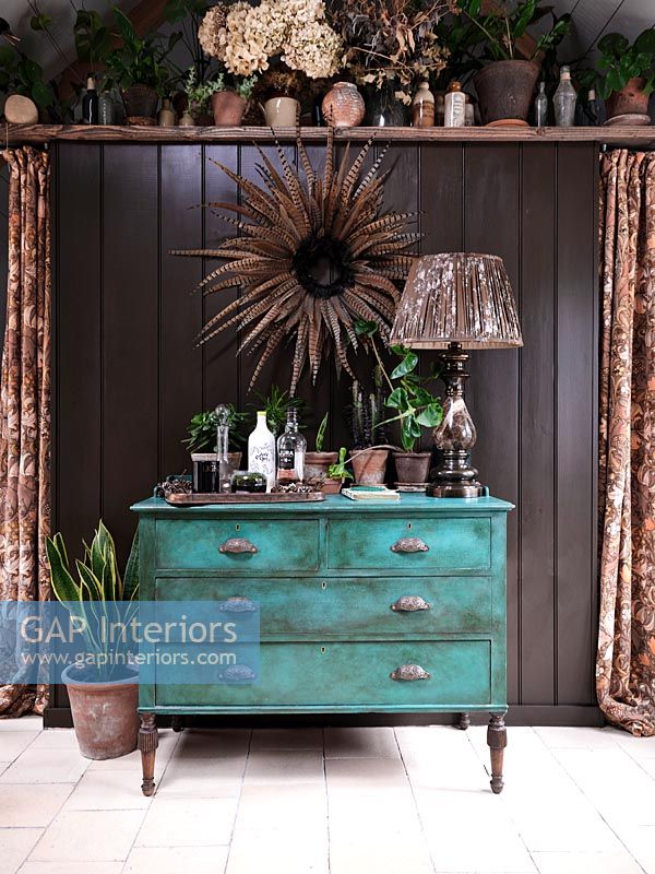 Teal painted chest of drawers against black wall 