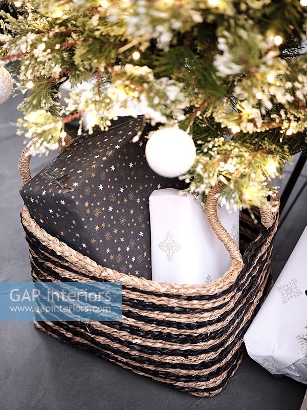 Black and gold Christmas gifts in basket under tree 