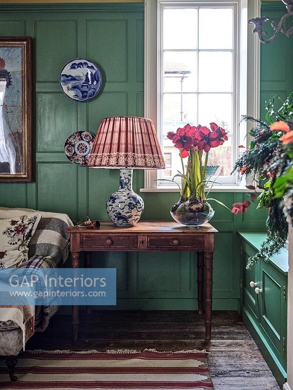 Flowers and lamp on antique side table in colourful classic living room 