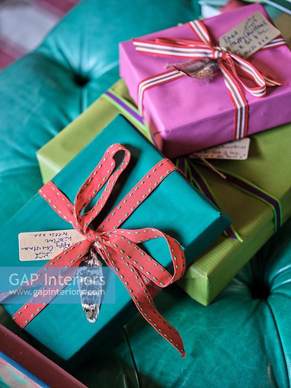 Colourfully wrapped Christmas presents with feathers, ribbons and gift tags
