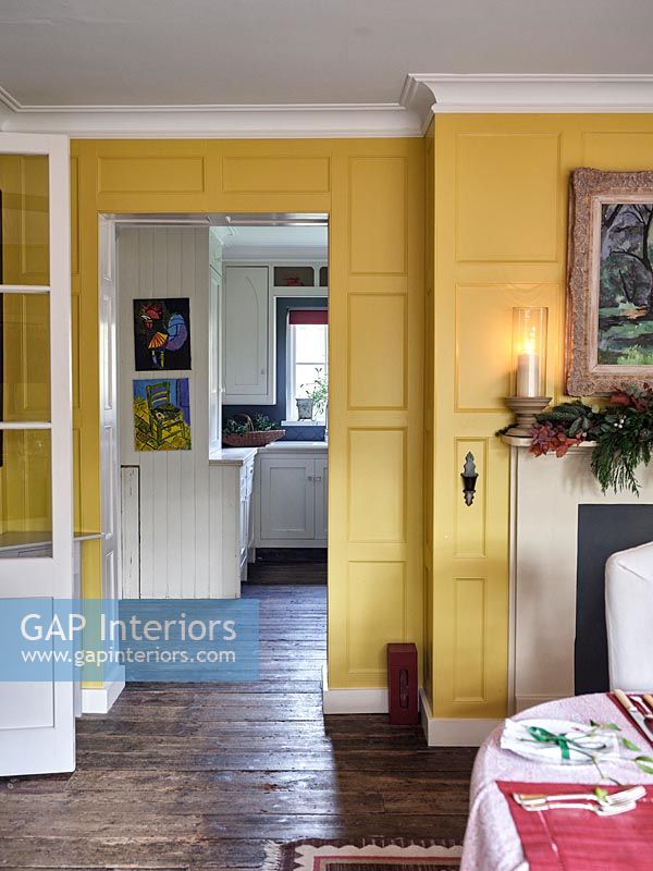 View into kitchen from yellow painted panelled dining room 